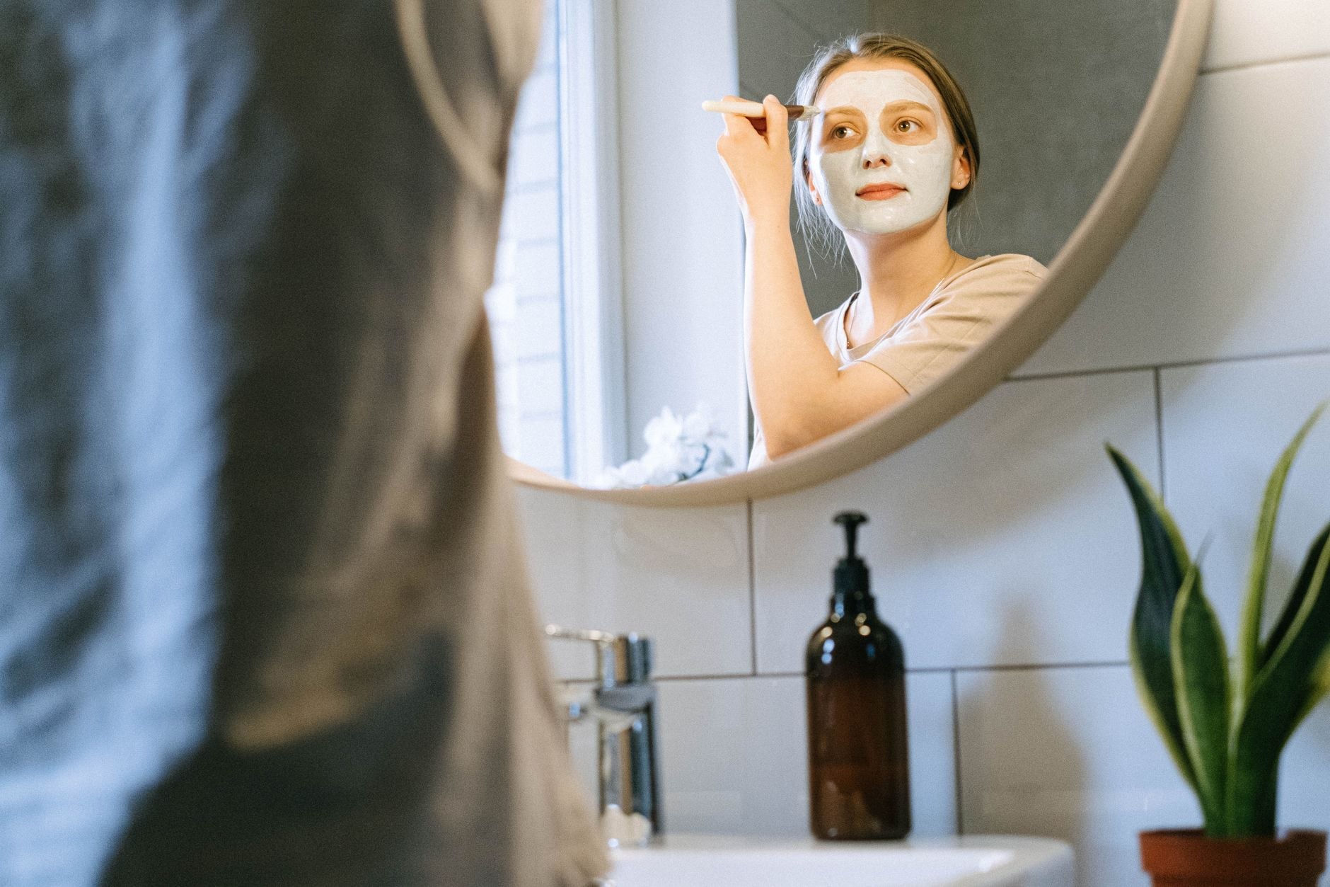 Woman applying facial mask clay with brush